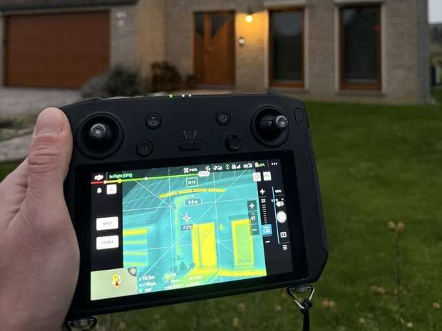 Drone en vol devant une toiture, écran de contrôle affichant l'image infrarouge